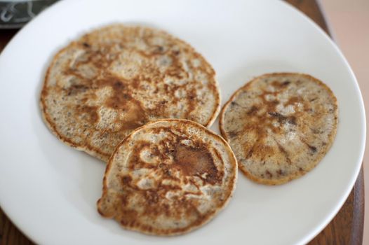 Three homemade fried chocolate chip pancakes served on a white plate in a high angle view