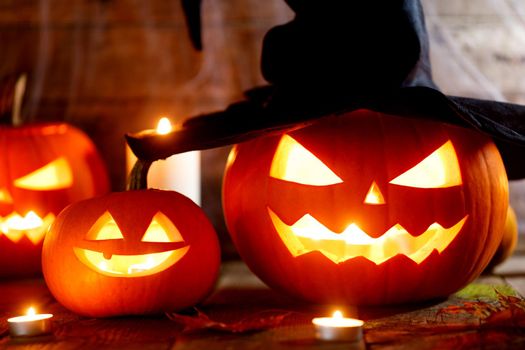 Festive mystical halloween interior. Pumpkin, spider web, burning candles, spiders on dark wooden background