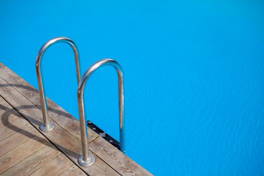 Ladder stainless handrails for descent into swimming pool. Swimming pool with handrail . Ladder of a swimming pool. People swim and relax in the pool
