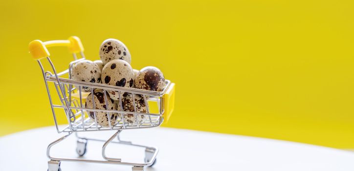 Happy Easter background. Easter quail eggs in the shopping cart on bright yellow paper. Festive concept.