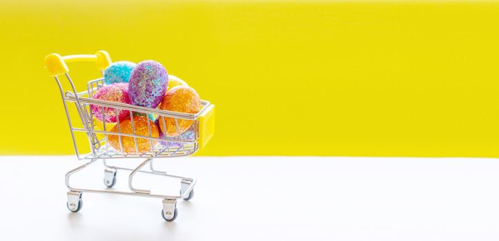 Happy Easter background. Easter multi-colored eggs in a basket on bright yellow paper. Festive concept.