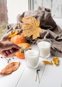 Hello fall. Cozy warm image. High angle view autumn composition with sweaters and candles, white candle mockup design