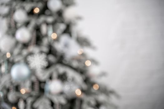 Close-up of a festively decorated outdoor Christmas tree with balls on a blurred sparkling fairy background. Defocused garland lights, bokeh effect