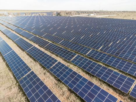 Aerial top view of a solar panels power plant. Photovoltaic solar panels at sunrise and sunset in countryside from above. Modern technology, climate care, earth saving, renewable energy concept