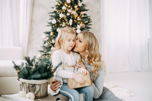 Happy family: mother and daughter. Family in a bright New Year's interior with a Christmas tree.