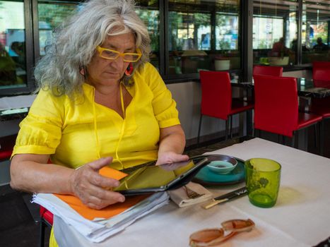 mature woman customer ordering food at restaurant using digital tablet