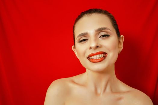 Portrait of a smiling beautiful young woman. Red background. Studio shot