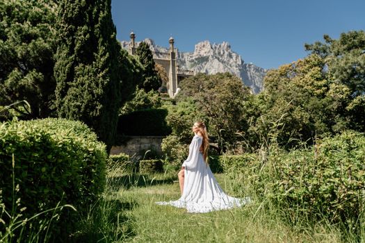 a beautiful woman with long brown hair stay along a path along beautiful bushes in the park