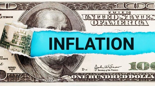Inflation World economics and inflation control concept. Torn bills revealing Inflation words. Idea for FED consider interest rate hike, US dollar inflation.