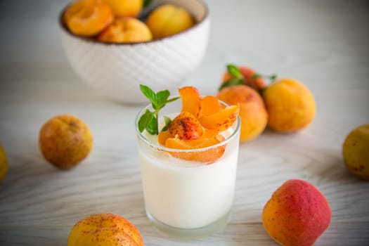 Healthy breakfast of homemade yogurt in a glass with fresh apricots on the table.
