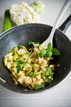 cauliflower fried with zucchini and vegetables in a pan with herbs