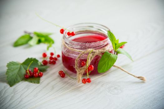 sweet summer jam from ripe red currants in a jar on a wooden table