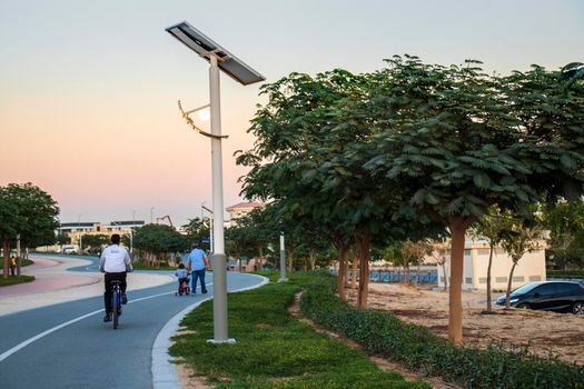 Jogging and cycling tracks in Al Warqa park, Dubai, UAE in the evening. Lamp post powered by solar panels can be seen in the picture.