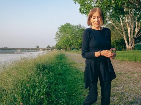 single female pensioner having fun in a park - aging free and wellness concept