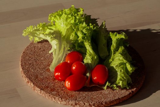 Salad leaves and cherry tomatoes on a wooden table. High-quality photo