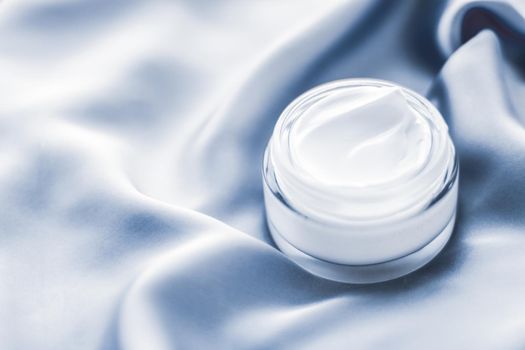 Spa, anti-age cosmetics and skincare concept - Beauty face cream jar on a soft blue silk