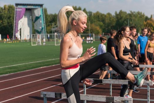 Young woman athlete runnner is exercising hurdles at the stadium outdoors