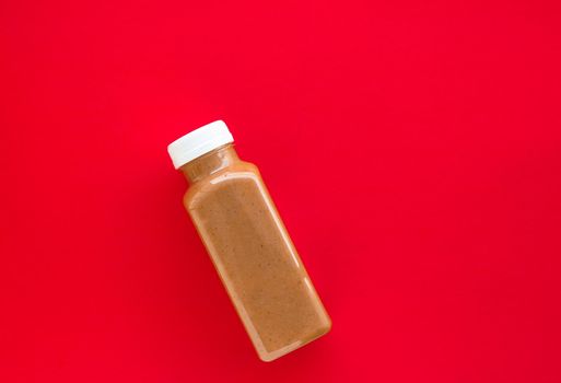 Detox, diet and healthy lifestyle concept - Chocolate banana smoothie bottle on red, flatlay