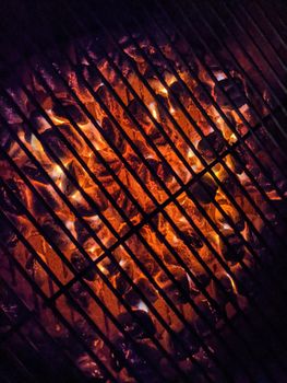 Red Hot Charcoal Coals burning with flames inside Grill at Night.