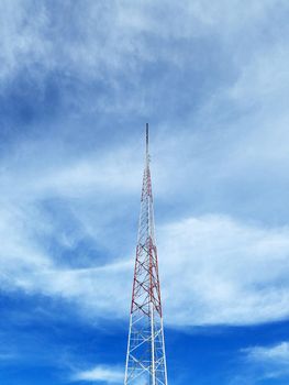 Red and White Communication tower against a cloudy sky in Hawaii.