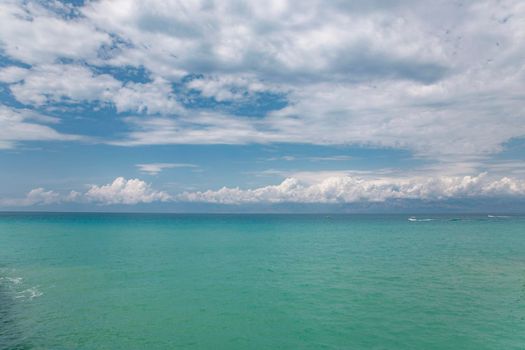 Beauty cloud against a blue sky background. Sky slouds. Blue sky with cloudy weather, nature cloud over the sea. Over the sea white clouds, blue sky and sun. High quality photo