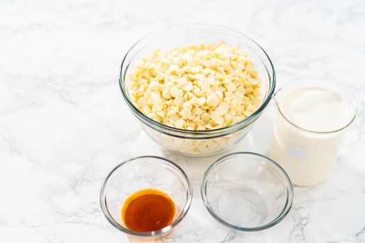 Measured ingredients in glass mixing bowls to make white chocolate ganache frosting.