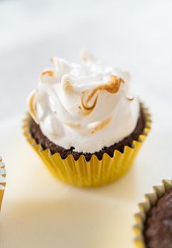 Frosting s'mores cupcakes with white meringue frosting.