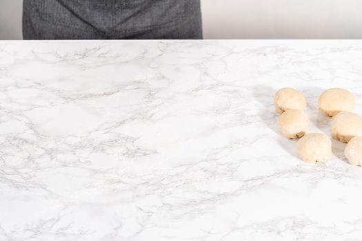 Shaping bread dough into a small ball to prepare dinner rolls.