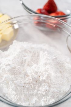 Ingredients in a glass mixing bowls to prepare the strawberry buttercream frosting.