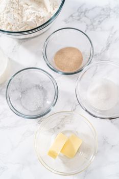 Measured ingredients in a glass mixing bowl to prepare dinner rolls.