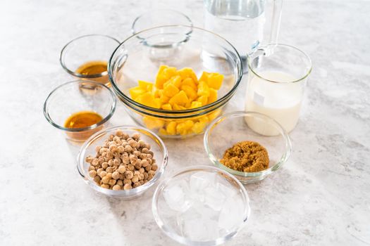 Flat lay. Measured ingredients in glass mixing bowls to prepare mango boba smoothie.