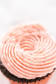 Chocolate cupcakes frosted with strawberry buttercream frosting.