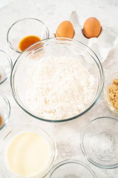 Measured ingredients in glass mixing bowls to bake eggnog scones.