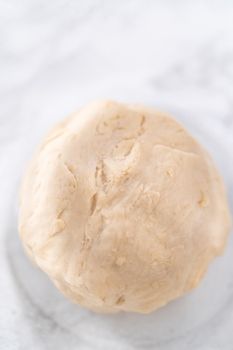 Rising dough in a glass mixing bowl to prepare dinner rolls.