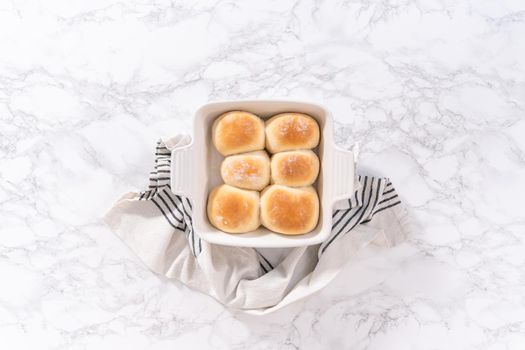 Flat lay. Freshly baked dinner rolls in a white ceramic dish.