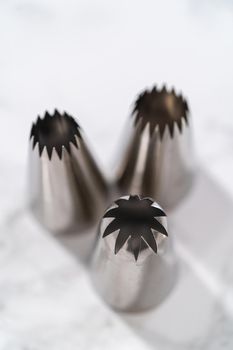 Jumbo piping metal tip with a piping bag on a kitchen counter to frost cupcakes.