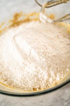 Mixing ingredients in a large glass mixing bowl to bake eggnog scones.