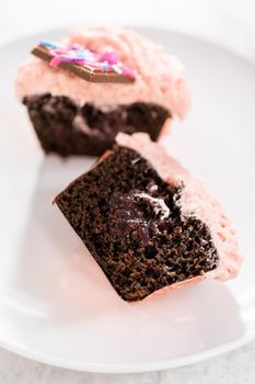 Slicing freshly baked chocolate strawberry cupcakes garnished with gourmet mini pink chocolates.