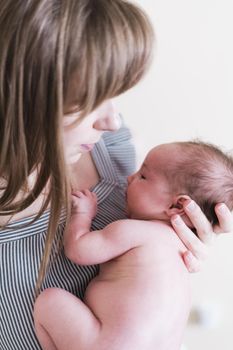 Lifestyle portrait of a young mother and her newborn, three weeks old daughter.