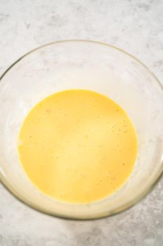 Mixing ingredients in a large glass mixing bowl to bake eggnog scones.