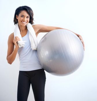 Holding the tools to fitness. A fit young beauty with a towel wrapped around her neck holding a medicine ball