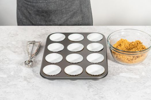 Filling cupcake liners with graham crackers to baking s'mores cupcakes.