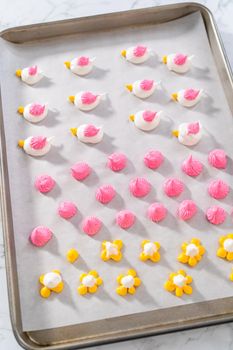 Piping meringue with piping bags into the baking sheet lined with parchment paper to bake Easter meringue cookies.