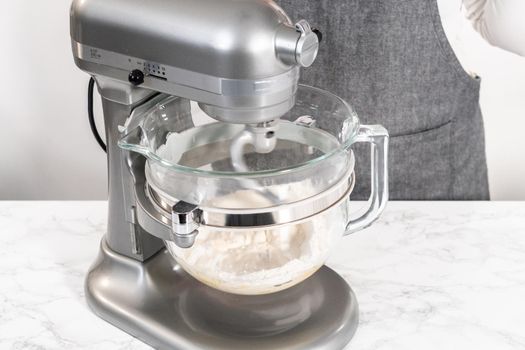 Kneading bread dough in a kitchen mixer with a dough hook to prepare dinner rolls.