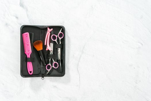 Flat lay. New barber set with pink scissors on a gray background.