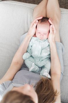 Lifestyle portrait of a young mother and her newborn, three weeks old daughter.