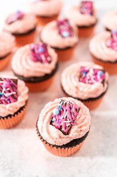 Freshly baked chocolate strawberry cupcakes garnished with gourmet mini pink chocolates.