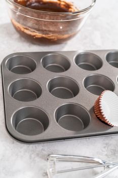 Scooping cupcake batter into the cupcake liners to bake chocolate strawberry cupcakes.