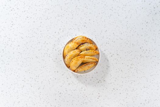 Flat lay. Freshly baked sweet empanadas with blueberries on the kitchen counter.