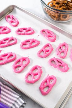 Dipping pretzels twists into melted chocolate to make chocolate-covered pretzel twists.